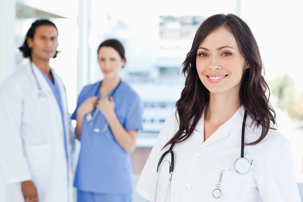 Smiling nurse standing in front of two co-workers